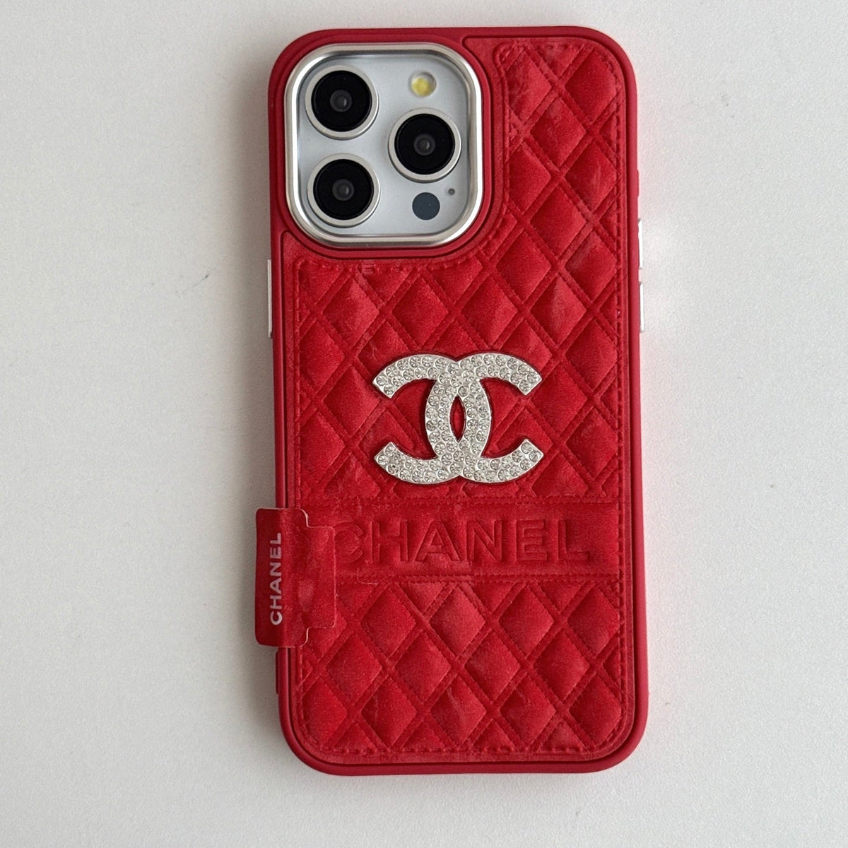 Red quilted iPhone case with a back grip strap and silver-tone emblem