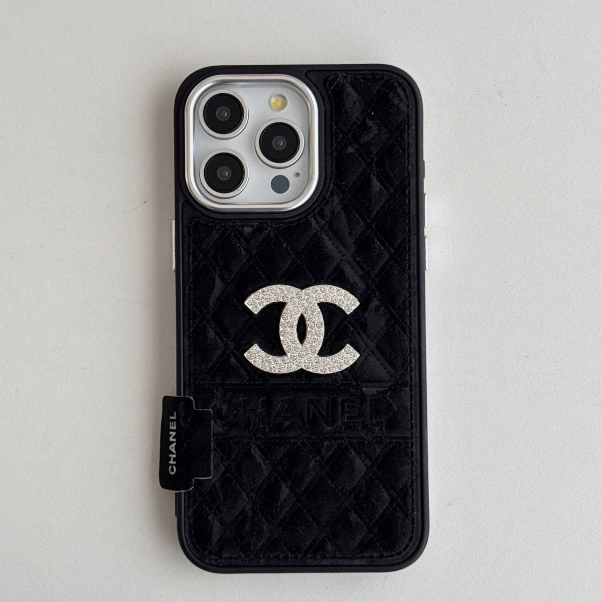 Black quilted iPhone case with a wide back strap and silver-tone emblem