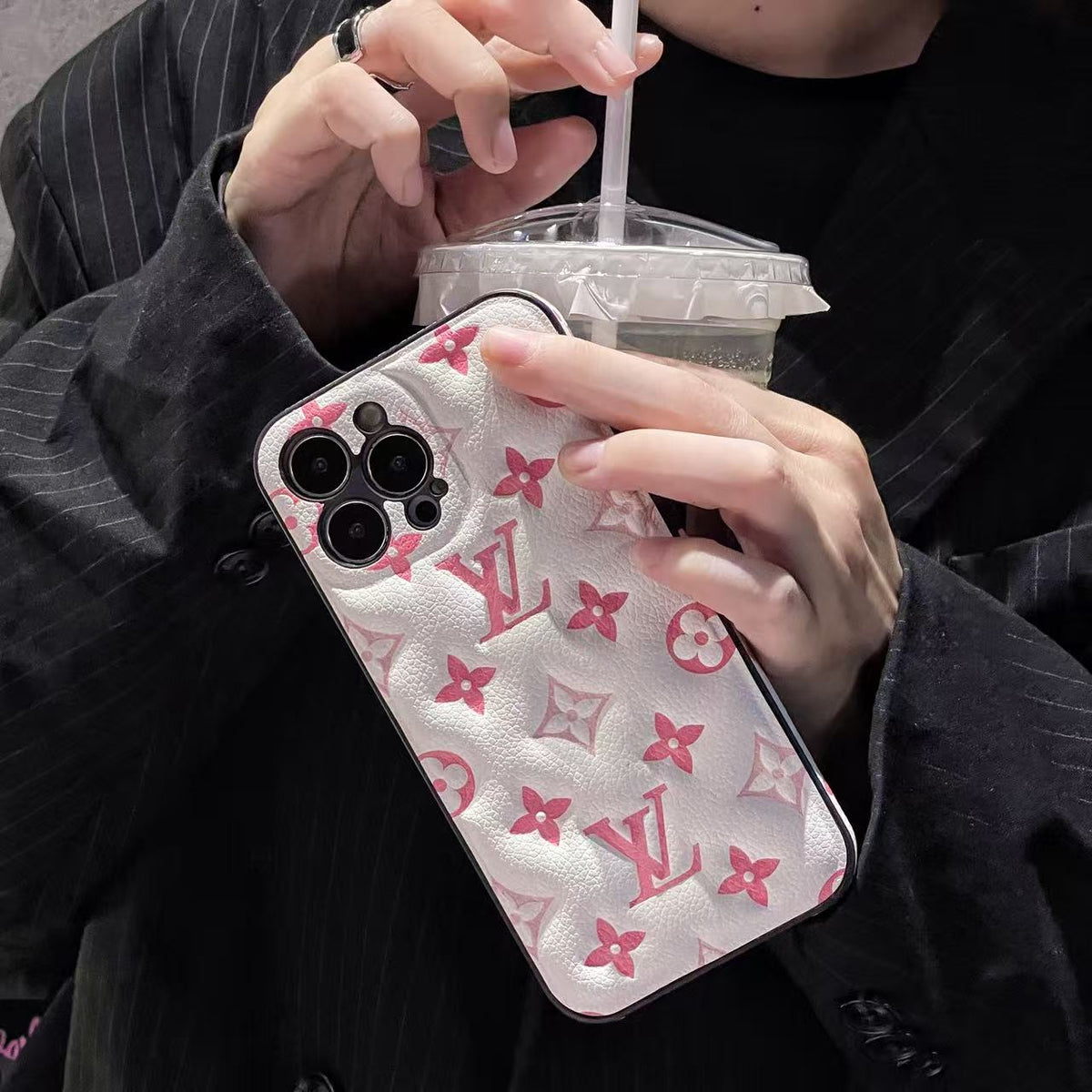 Clear pink monogram iPhone case shown in a hand-held product view