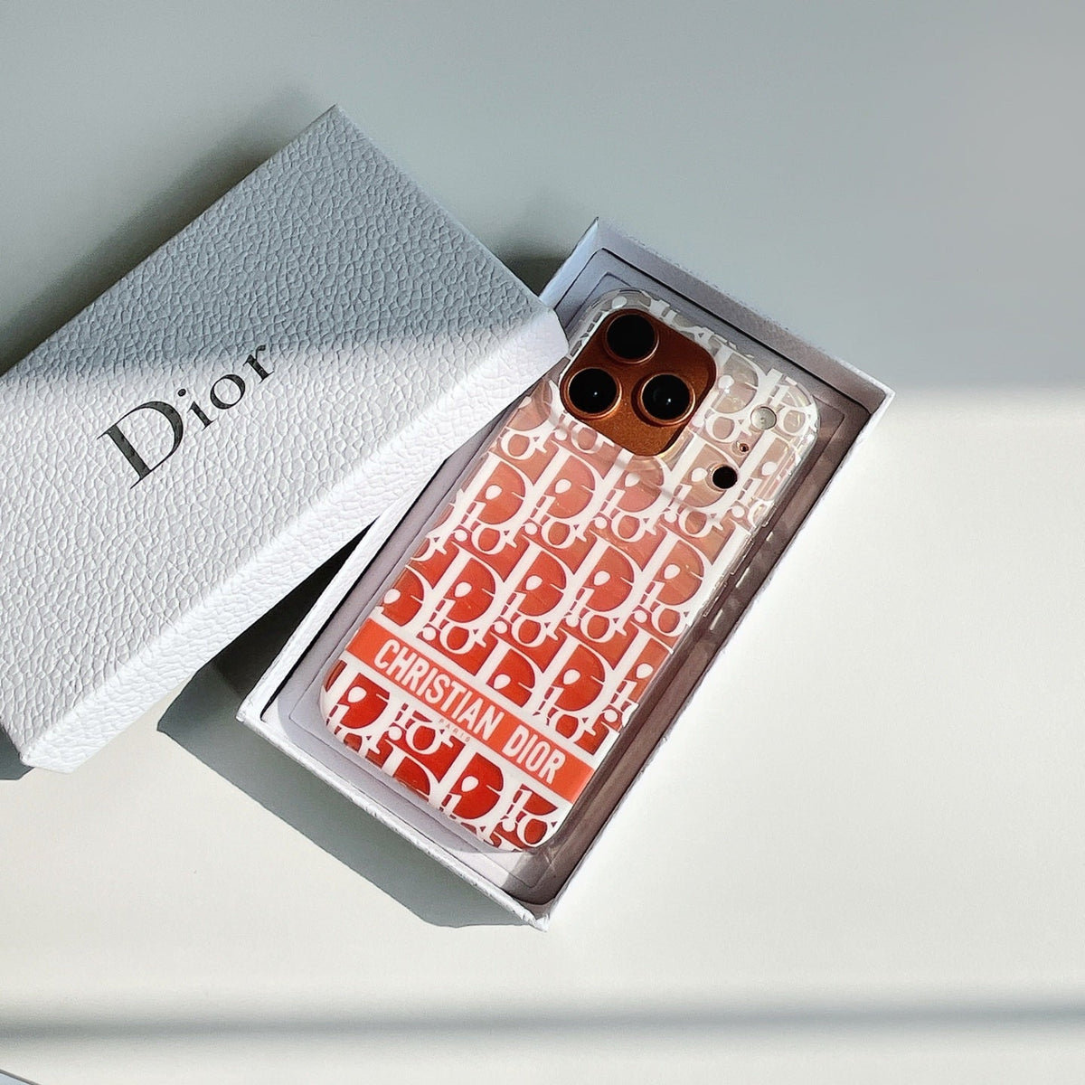 Coral monogram-print iPhone case displayed in a presentation box