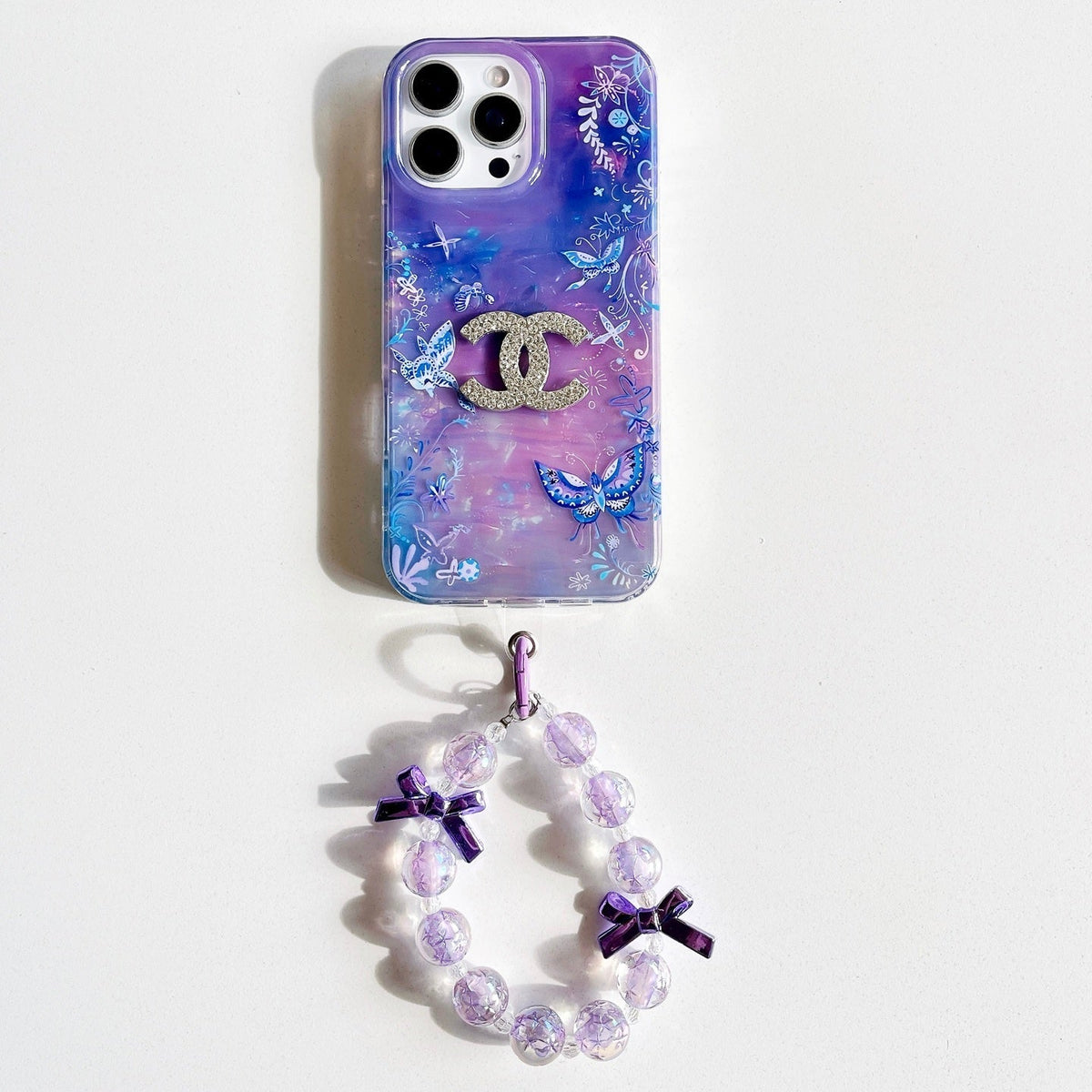 Purple and blue marble-effect iPhone case with butterfly details and a beaded wrist strap