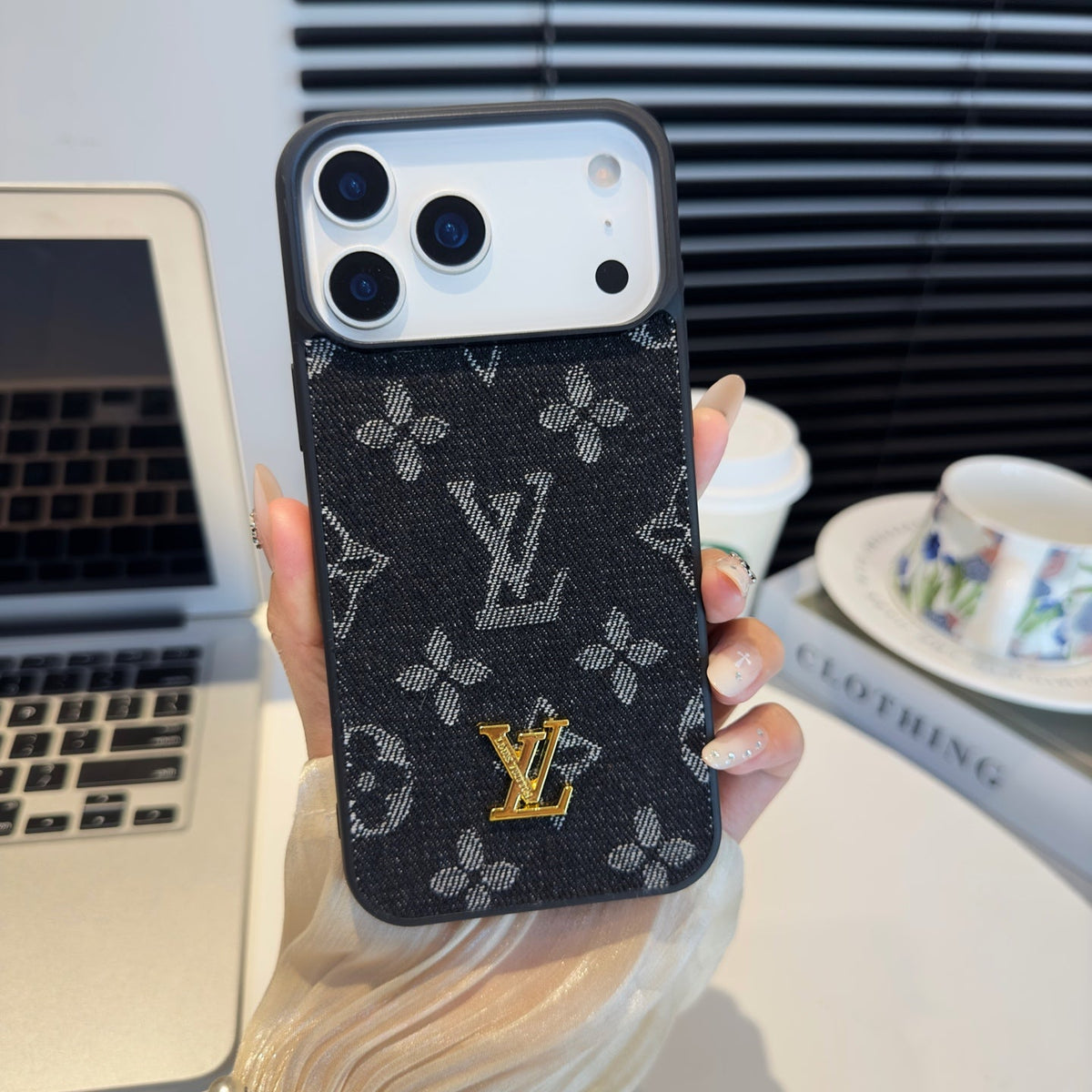 Black and gray monogram iPhone case with a raised gold-tone center emblem