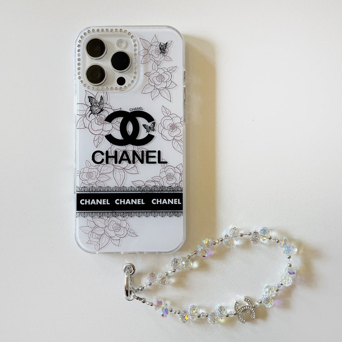 White floral logo iPhone case with a pearl-style wrist strap
