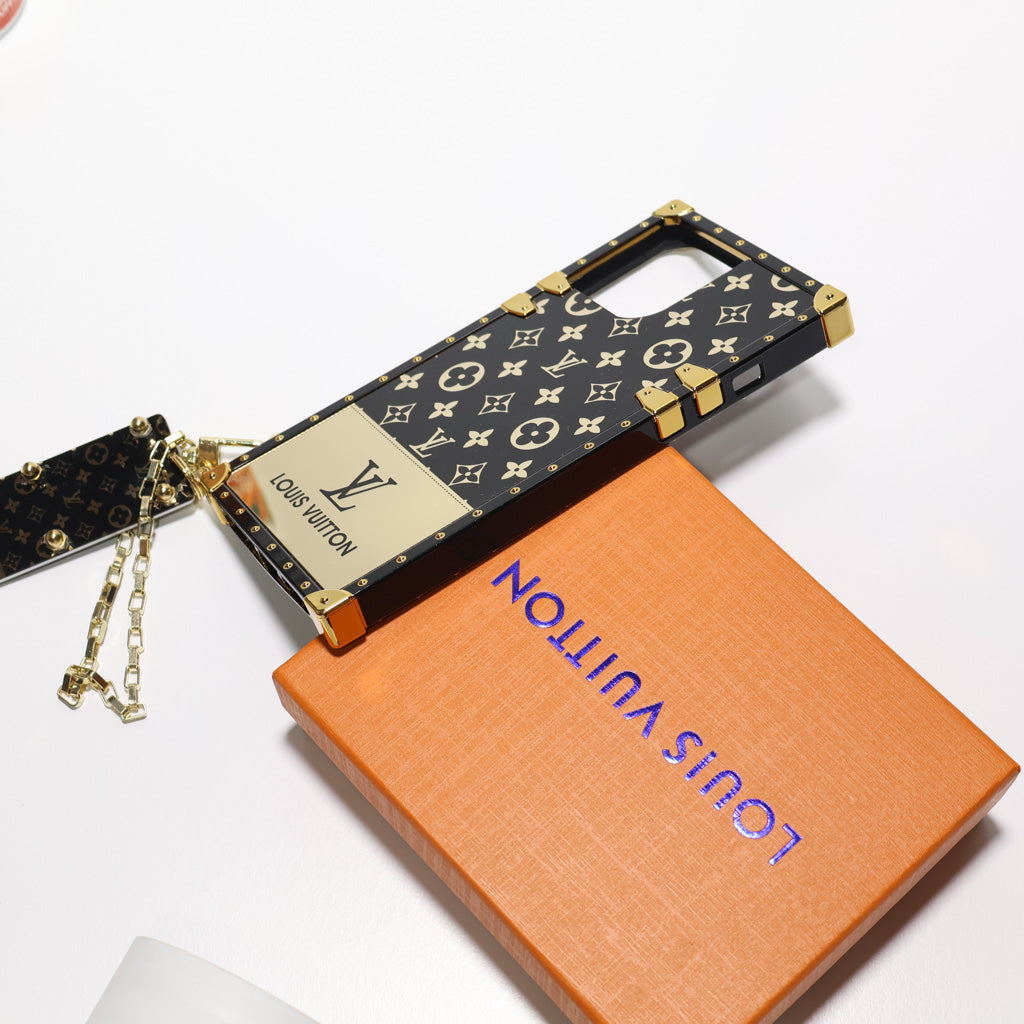 Golden monogram LV Eye Trunk iPhone case showing the glossy finish and reinforced edges