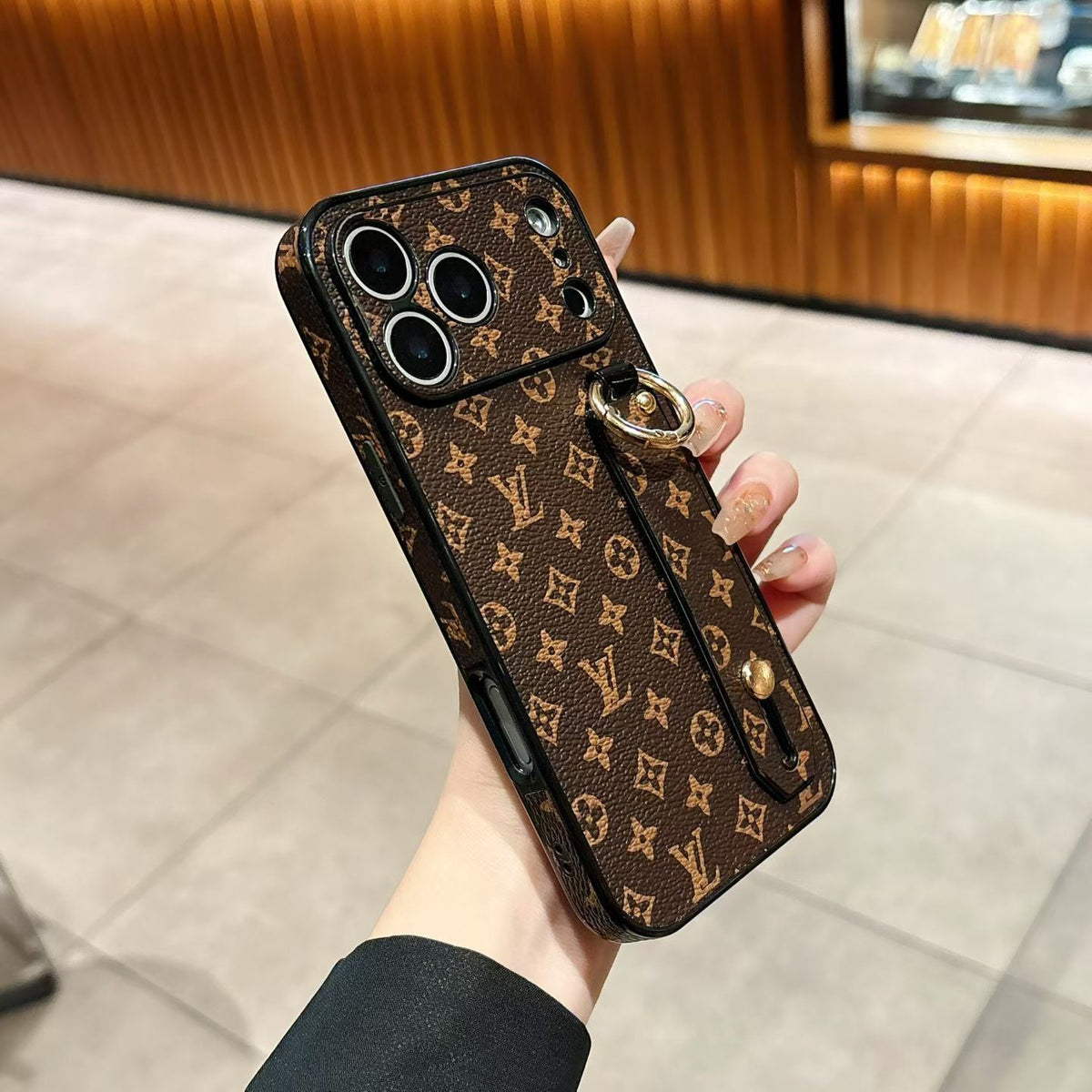 Close-up of the LV hand strap iPhone case showing the grip feature and leather finish