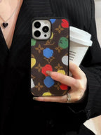 LV paint spots iPhone case shown as a fashion styling accessory with the patterned back visible