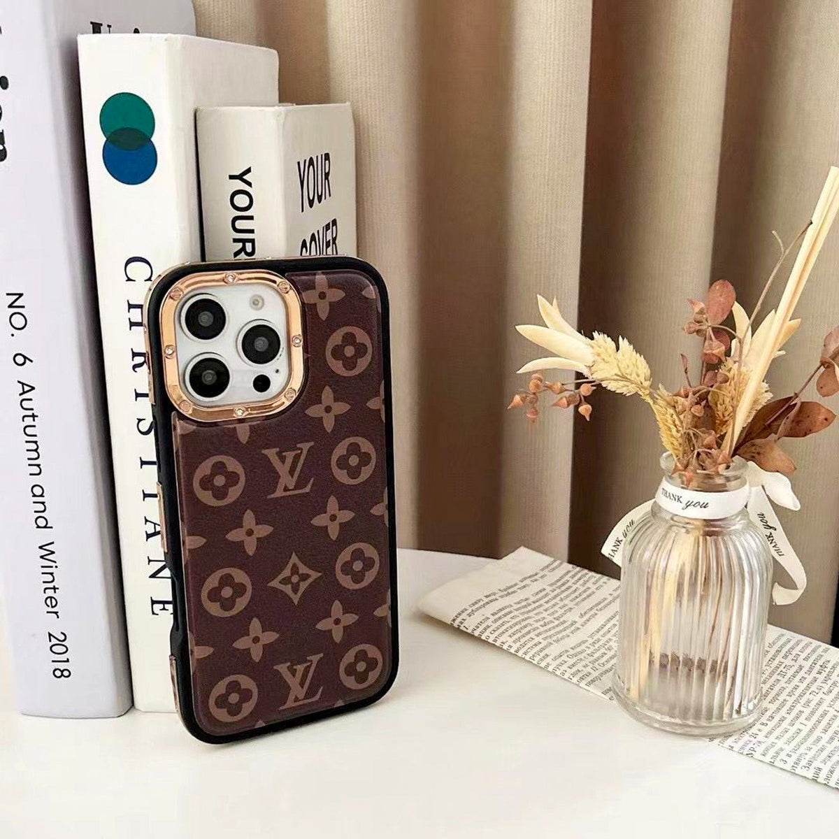 Monogram LV iPhone case shown from the back with gold-tone trim and protective fit