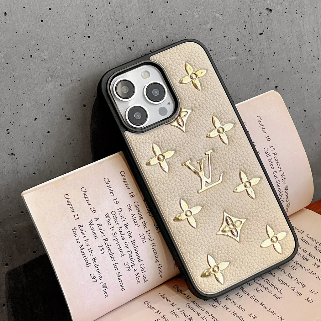 Golden monogram iPhone case close-up showing the patterned leather back and fitted camera cutout