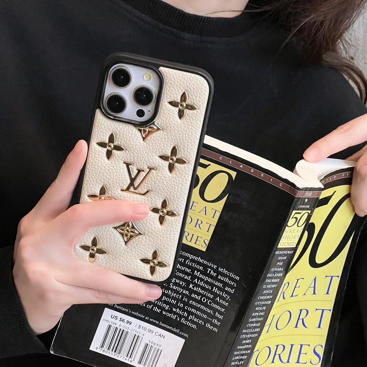 Close-up of the golden monogram leather iPhone case highlighting the metallic pattern and texture