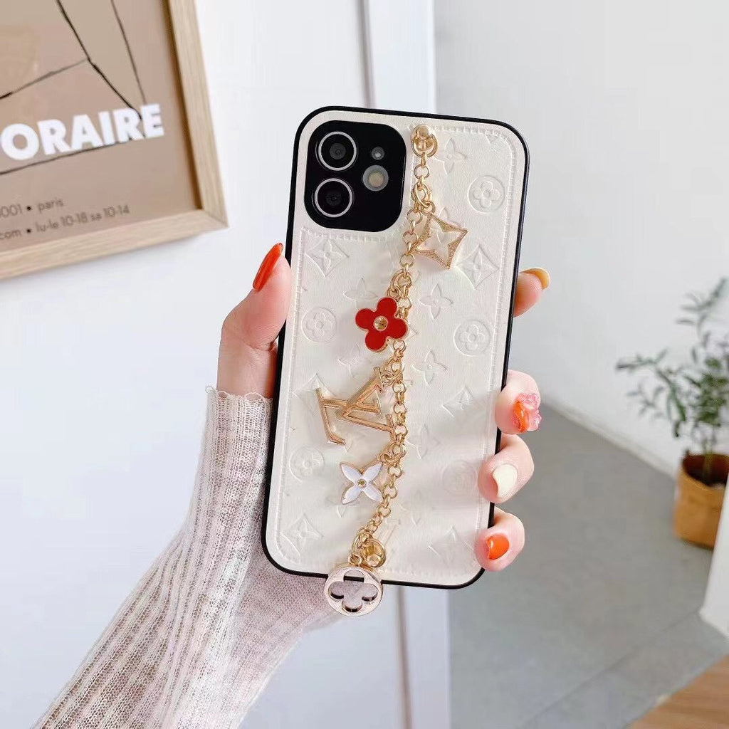 White LV ornament iPhone case showing the wrist strap, leather finish and protective edges