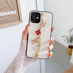 White LV ornament iPhone case showing the wrist strap, leather finish and protective edges