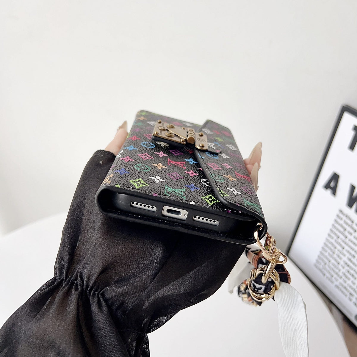 Crossbody wallet iPhone case showing the colorful patterned back and carrying strap