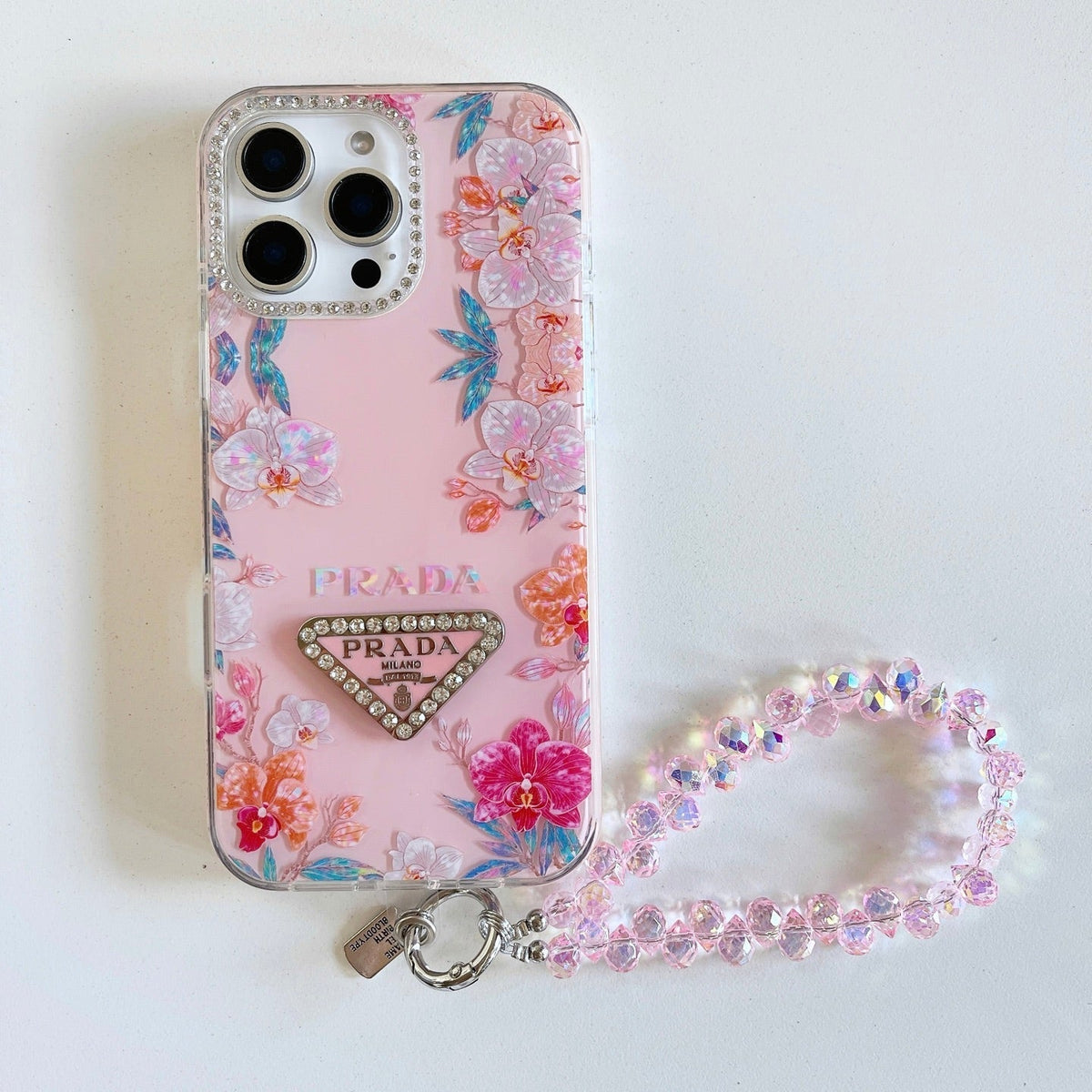 Pink floral iPhone case with a beaded wrist strap and triangular emblem