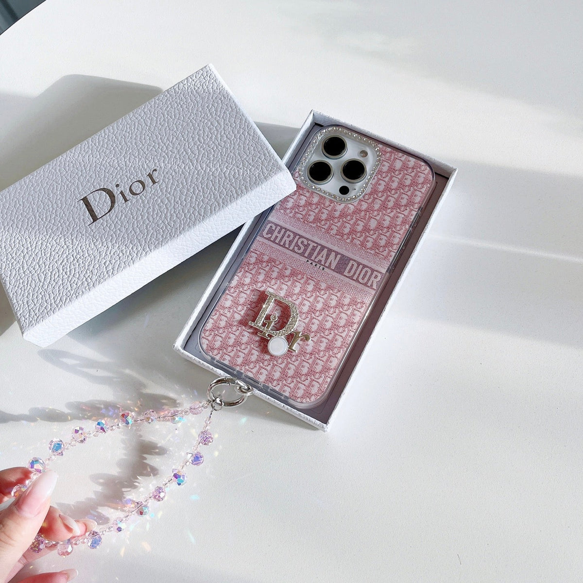 Pink patterned iPhone case with a central strap detail and beaded wristlet