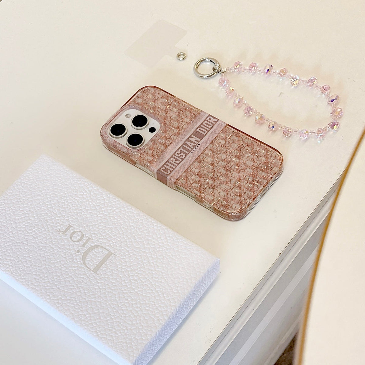 Blush monogram-print iPhone case with a beaded wrist strap in a close-up product view