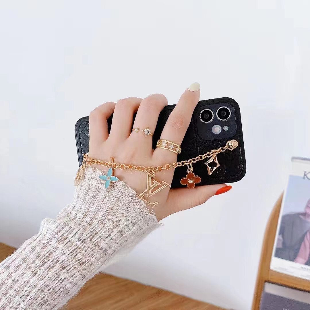 Black LV ornament iPhone case shown in a lifestyle view with the wrist strap attached