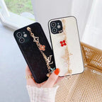 White LV ornament iPhone case shown in hand with the decorative wrist strap and leather back